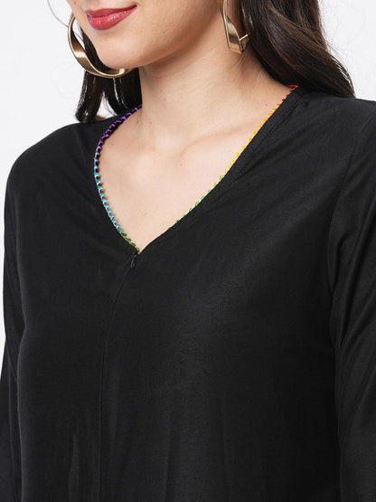 Hashtag Be featuring a black silk blend below calf jumpsuit with multi color trim at the neck and sleeve hem