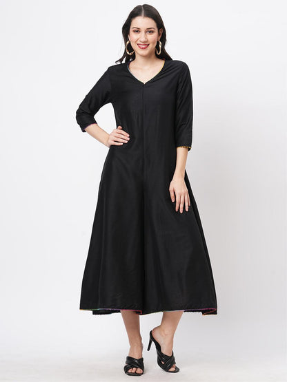 Hashtag Be featuring a black silk blend below calf jumpsuit with multi color trim at the neck and sleeve hem
