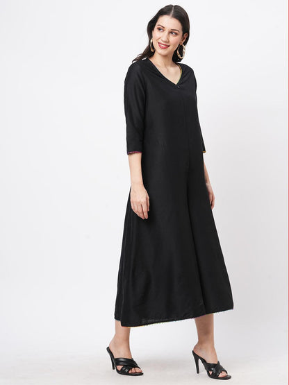 Hashtag Be featuring a black silk blend below calf jumpsuit with multi color trim at the neck and sleeve hem
