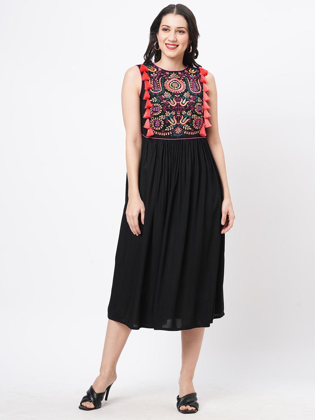 Hashtag Be Featuring a black boho calf length airy dress with tassel and embroidery